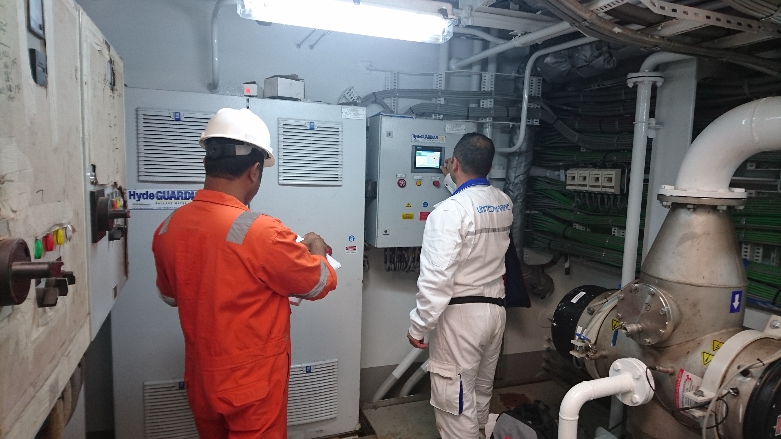 Engineers at a BWMS control cabinet during servicing